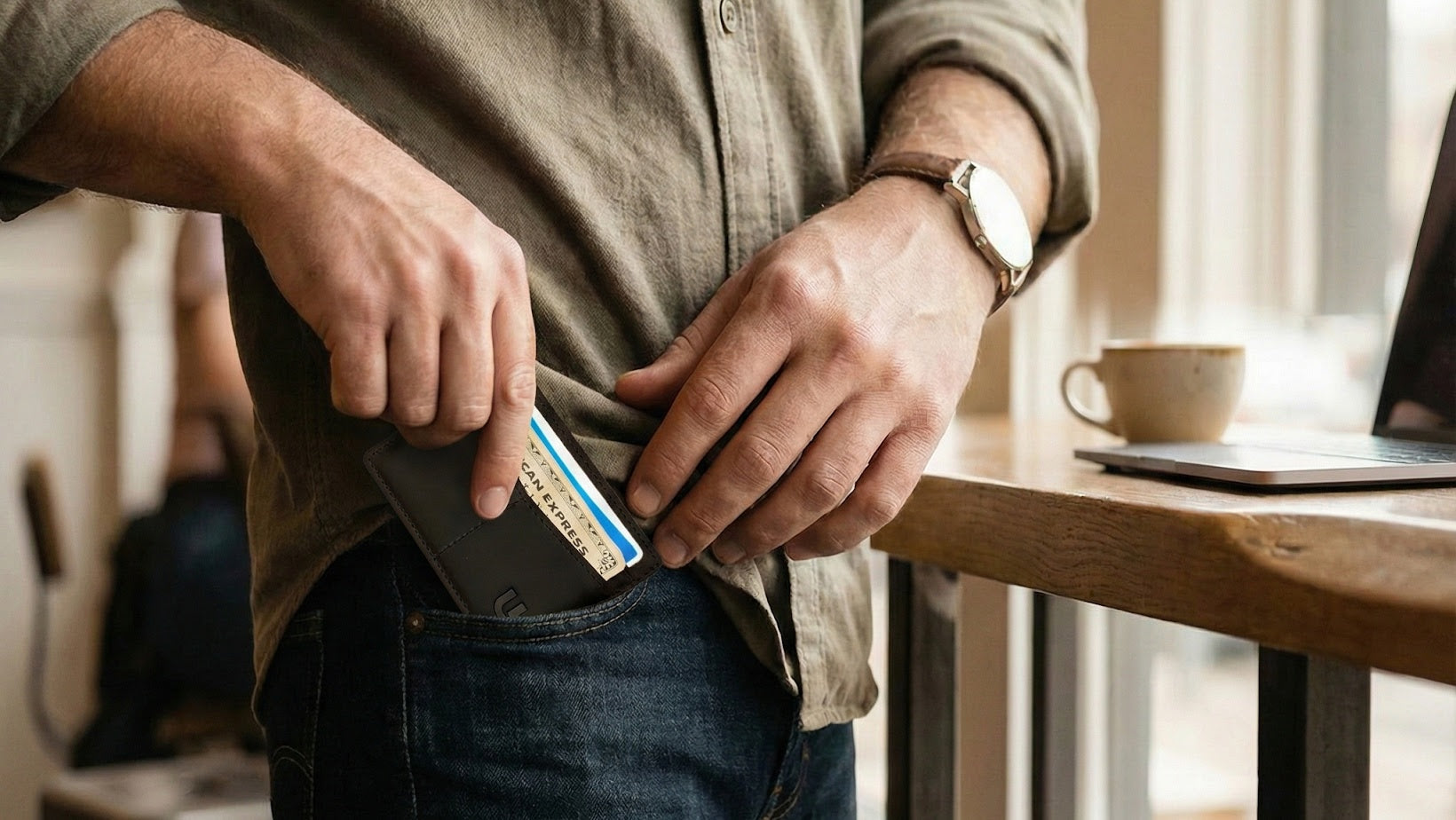 a man putting brown his card holder  away in his jeans pocket